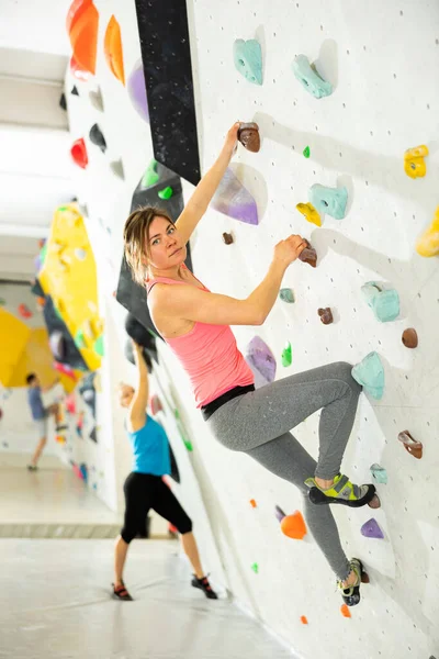 在没有安全带的人造卵石上练习室内攀岩的年轻女阿尔卑斯山师 — 图库照片