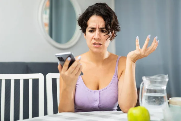Verärgerte Frau Sitzt Wohnung Tisch Und Telefoniert — Stockfoto