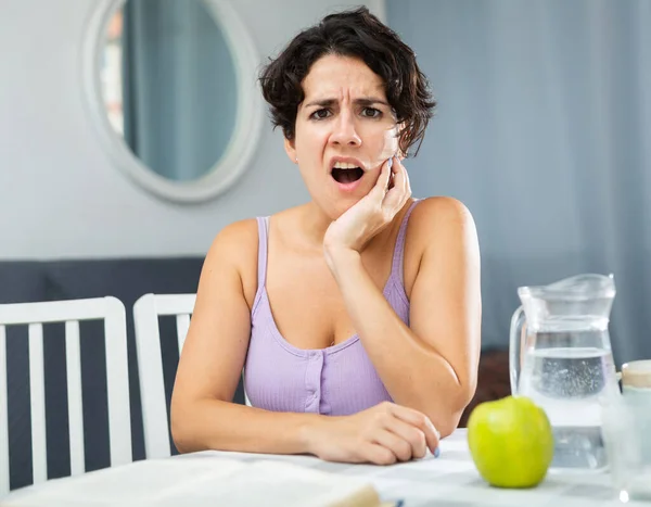 Young Woman Having Toothache Touching Cheek Sitting Table Apartment — Stock Photo, Image