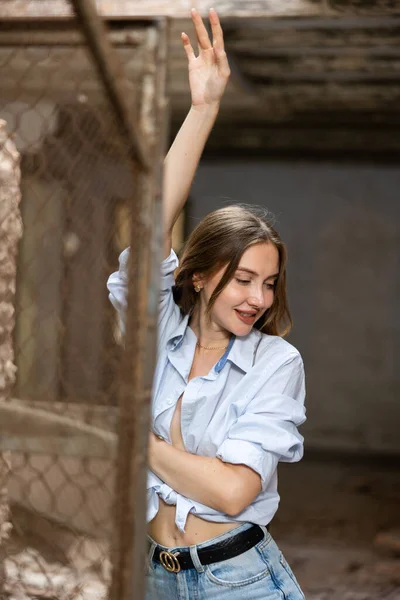 穿着衬衫 在废弃的建筑物里摆姿势 面带微笑的年轻可爱的快乐女人 — 图库照片