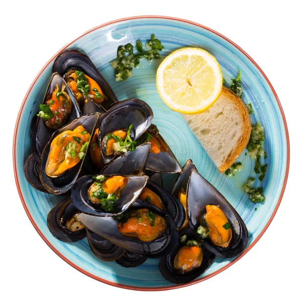 stock image Top view of steamed mussels in garlic herb sauce served with bread slice and lemon on blue ceramic dish. Isolated over white background