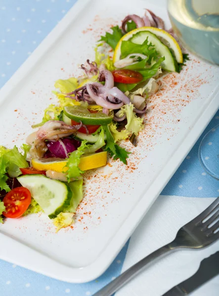 stock image Close up of tasty salad of boiled squids, lemon and lettuce leaves