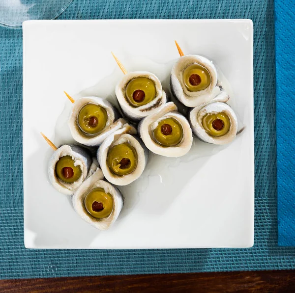 白皿に盛り付けられたパプリカを詰めたオリーブのマリネしたニシンの切り身の風味豊かなロールのトップビュー — ストック写真