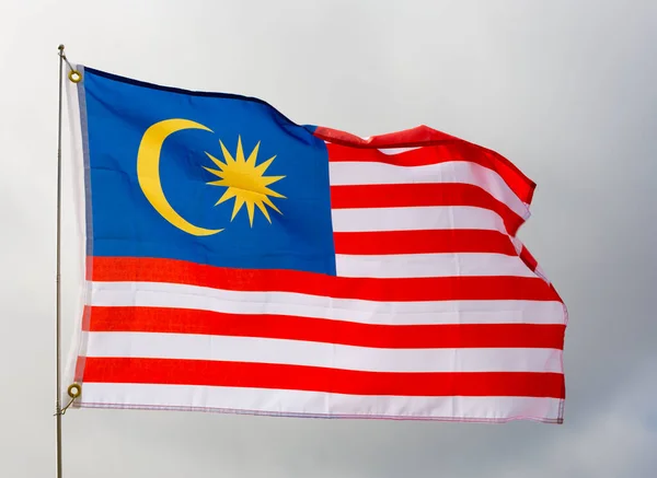 昼間の曇天を背景に金属製の棒で固定されたマレーシアの大きな旗 — ストック写真