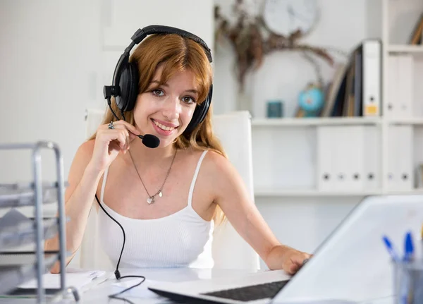 迷人的年轻女性在呼叫中心工作时使用带麦克风和笔记本电脑的耳机 — 图库照片