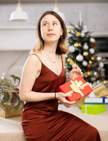 Συγκεντρωμένη Νεαρή Γυναίκα Θέλει Ανοίξει Ένα Χριστουγεννιάτικο Δώρο Ενώ Στο — Φωτογραφία Αρχείου