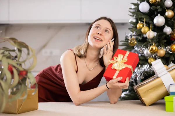 아가씨가 크리스마스 선물을 준비하고 있습니다 전화로 누군가와 이야기하면서 말이죠 — 스톡 사진