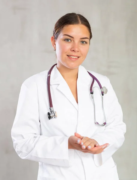 Дружня Молода Жінка Професійний Лікар Білому Пальто Позує Сірому Студійному — стокове фото