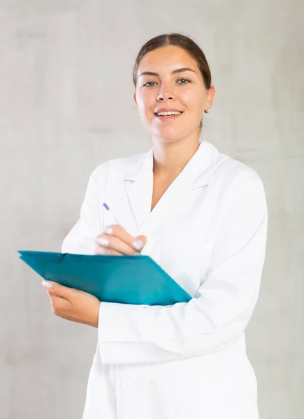 Gülümseyen Kadın Doktor Elinde Kağıtlarla Ayakta Duruyor Yazıyor — Stok fotoğraf
