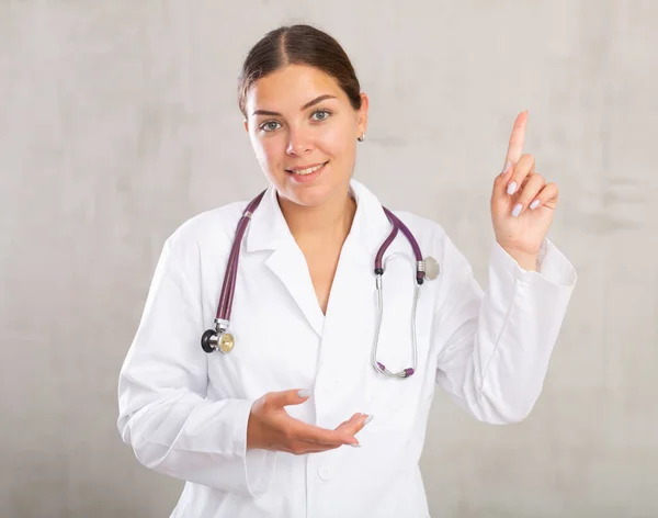 Жінка Лікар Білому Пальто Посміхається Камери Представляючи Рукою Вказуючи Пальцем — стокове фото