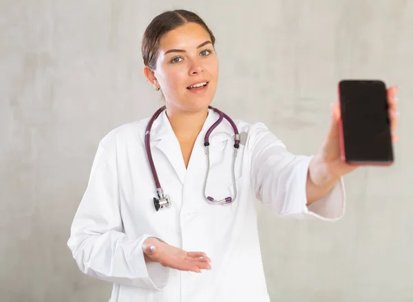Усміхнена Жінка Лікар Показує Екран Свого Смартфона — стокове фото