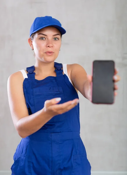 Vrolijke Vrouwelijke Werknemer Overalls Met Scherm Van Haar Telefoon — Stockfoto