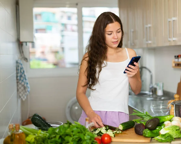 家庭主妇在厨房做饭时使用手机 — 图库照片