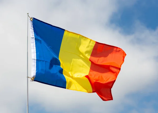 独立と晴れた日に曇りの空に対して旗竿になびく国の統一を象徴するカラフルな青 黄色と赤の国家ルーマニアの旗 — ストック写真