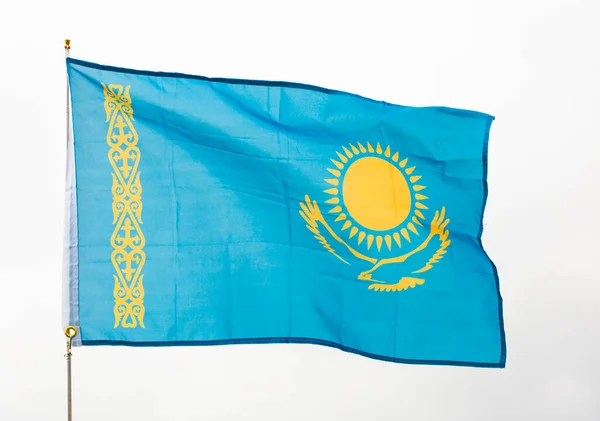 国家の誇りのための願望を反映して カザフスタンの文化と歴史を象徴する 黄金の高騰ワシと太陽と青い旗は カザフスタンの空に対して旗スタッフに手を振って — ストック写真