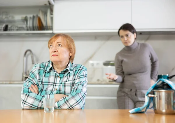 与女儿在家里厨房的餐桌旁发生冲突后 心烦意乱的成熟女人 — 图库照片