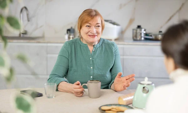 一个快乐的老妇人在厨房里笑着说话 — 图库照片