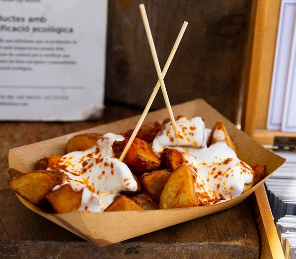 stock image Just cooked takeaway dish patatas bravas served on cardboard plate with sauce.