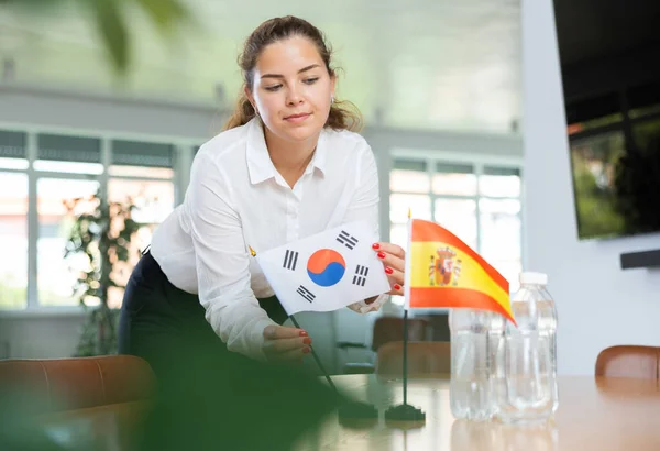 ビジネス服の若い女性は 韓国とスペインの国旗をオフィスで交渉テーブルに置きます — ストック写真