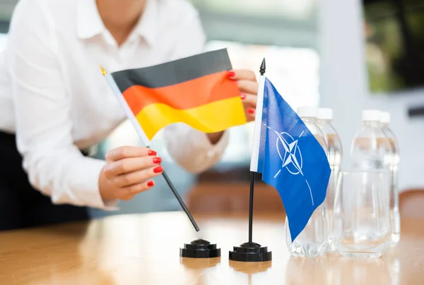 Jonge Vrouwelijke Assistent Opzetten Nato Duits Vlaggen Voor Internationale Onderhandelingen — Stockfoto