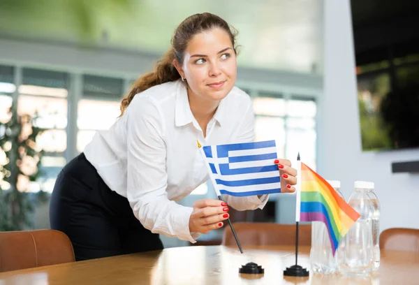 ビジネス服の若い女性はギリシャとLgbtの旗をオフィスの交渉テーブルに置きます — ストック写真