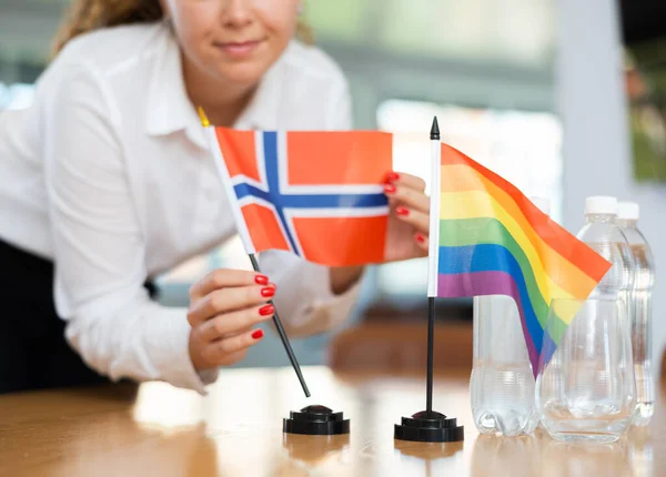 ビジネス服の若い女性はノルウェーとLgbtの旗をオフィスの交渉テーブルに置きます — ストック写真