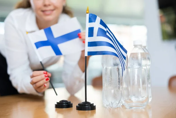 Jovem Assistente Montando Bandeiras Gregas Finlandesas Para Negociações Internacionais — Fotografia de Stock