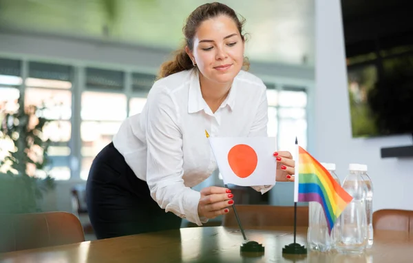 ビジネス服を着た若い女性が日本とLgbtの旗をオフィスの交渉テーブルに置きます — ストック写真