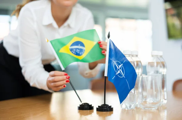 Νεαρή Γυναίκα Βοηθός Στήνει Σημαίες Νατο Και Βραζιλίας Για Διεθνείς — Φωτογραφία Αρχείου