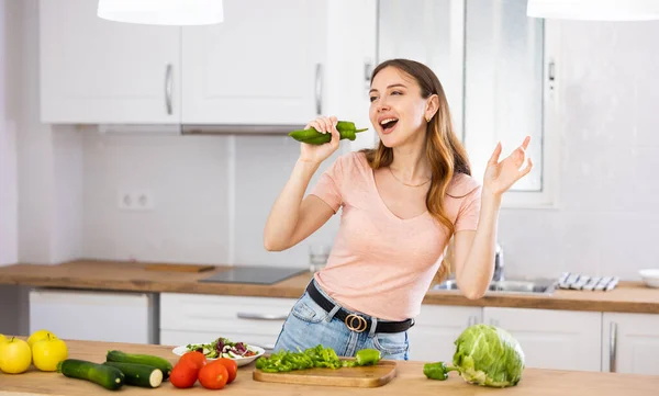 Genç Neşeli Bir Kadın Elinde Yeşil Biberle Evde Sebze Yemeği — Stok fotoğraf