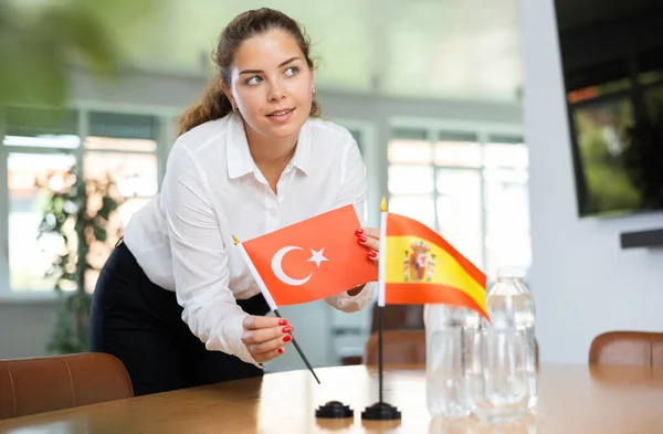 身穿商务服装的年轻女性把土耳其和西班牙的国旗摆上谈判桌 — 图库照片