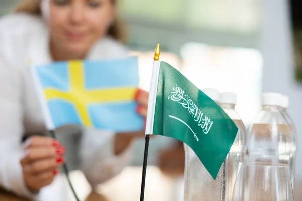 女国务卿为谈判准备了一个办公室 她把沙特阿拉伯和瑞典的国旗放在谈判桌前 — 图库照片