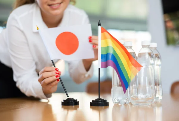 ビジネス服を着た若い女性が日本とLgbtの旗をオフィスの交渉テーブルに置きます — ストック写真