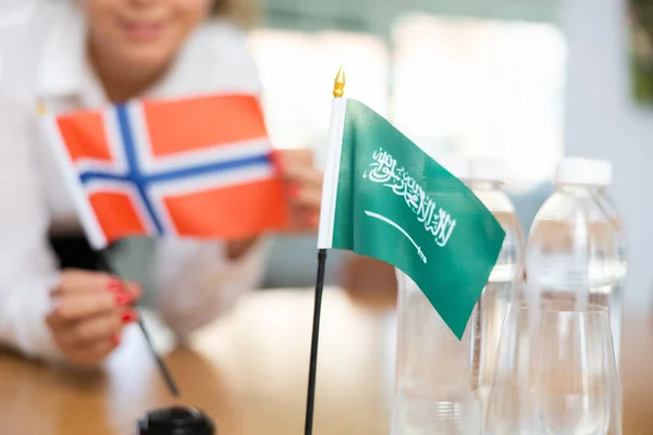 沙特阿拉伯的小国旗 水瓶和挪威的国旗被积极的年轻女子放在旁边 — 图库照片