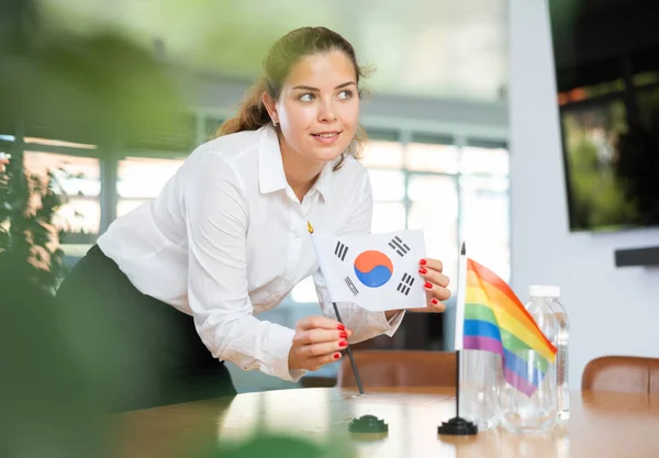 ビジネス服を着た若い女性が韓国とLgbtの旗をオフィスの交渉テーブルに置きます — ストック写真