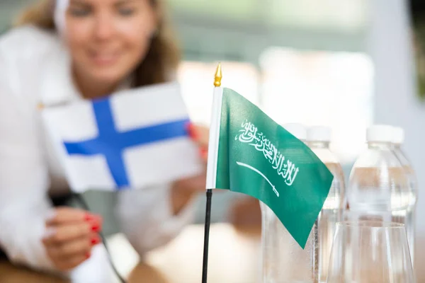 女国务卿为谈判准备了一个办公室 她把沙特阿拉伯和芬兰的国旗放在谈判桌前 — 图库照片