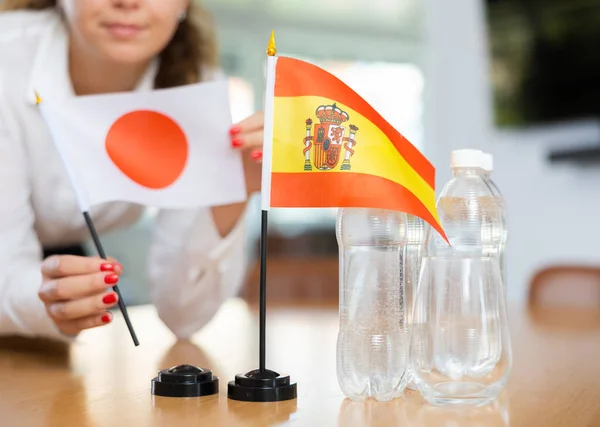 Egy Fiatal Üzleti Ruhában Japán Spanyol Zászlókat Tesz Tárgyalóasztalra — Stock Fotó