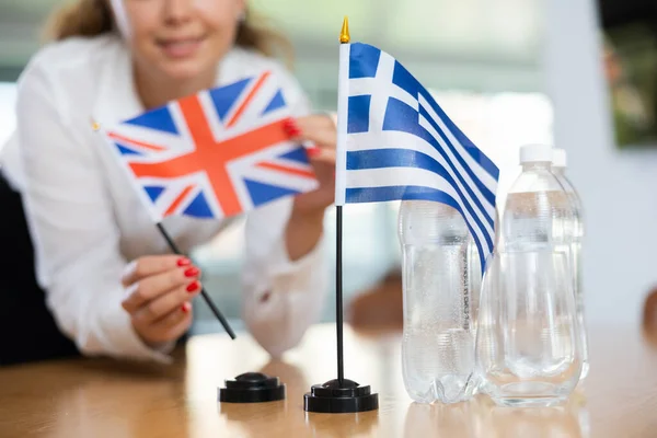 Молодая Ассистентка Устанавливает Греческие Британские Флаги Международных Переговоров — стоковое фото