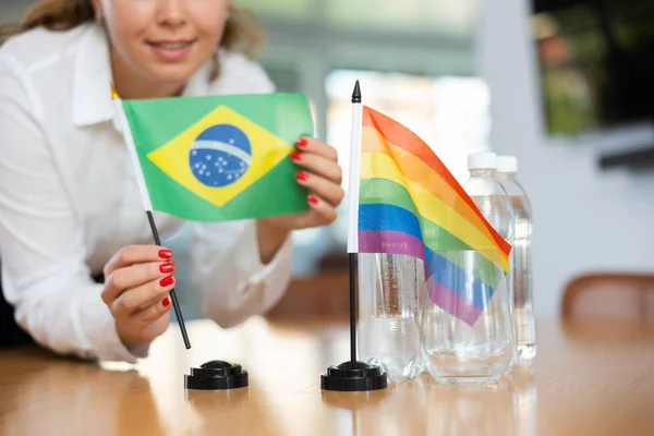 ビジネス服の若い女性は オフィスで交渉のテーブルにブラジルとLgbtのフラグを置きます — ストック写真