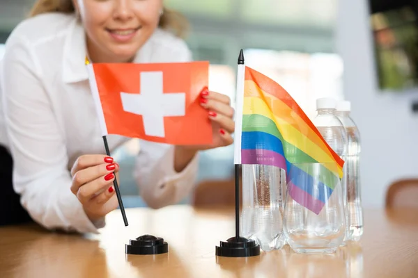 Jonge Vrouw Bedrijfskleding Zet Vlaggen Van Zwitserland Lgbt Onderhandelingstafel — Stockfoto