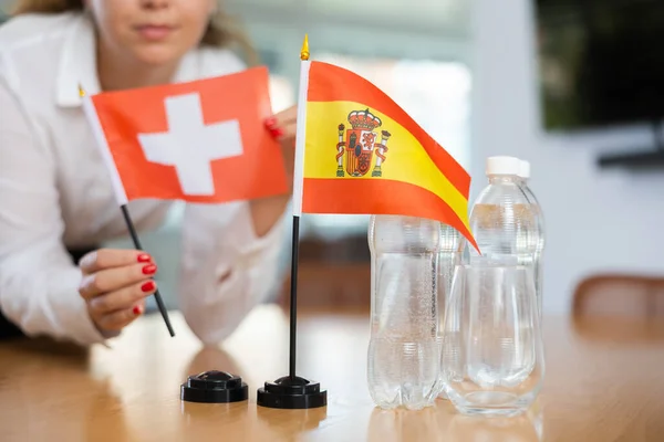 Молода Жінка Діловому Одязі Ставить Прапори Швейцарії Іспанії Стіл Переговорів — стокове фото