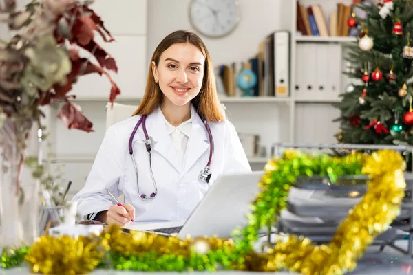 Giovane Donna Medico Caucasico Seduto Tavola Ufficio Decorato Durante Natale — Foto Stock