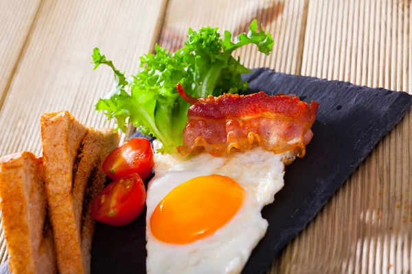 Πρωινό Τηγανητό Αυγό Σερβιρισμένο Μπέικον Και Φρυγανιές Γαρνιρισμένο Ντοματίνια Και — Φωτογραφία Αρχείου