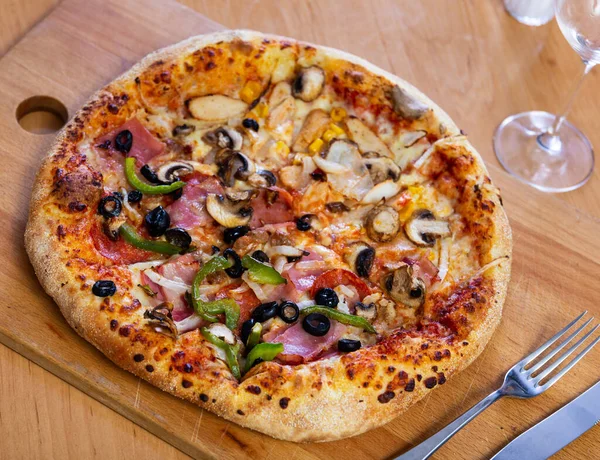 stock image Double pizza with salami, pepper, onion and olives on one half and mushrooms, canned corn and cheese on other half