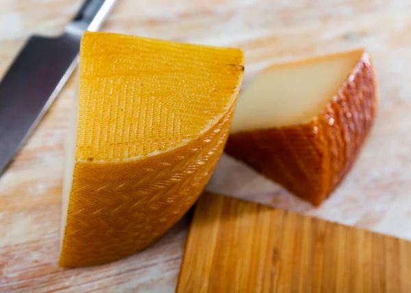 用牛乳在木制桌子上切成美味的西班牙半硬奶酪 — 图库照片