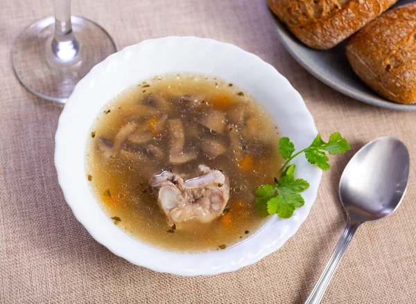 Hearty homemade soup with forest mushrooms, pork, vegetables and pearl barley. Russian cuisine