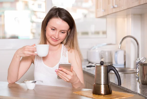 Dziewczyna Rozmawia Przez Telefon Pije Herbatę Przy Stole Jest Szczęśliwa — Zdjęcie stockowe