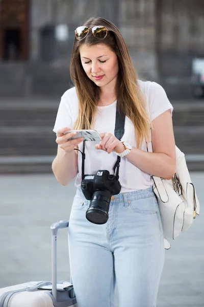 年轻快乐的美国旅行女孩在镇上用她的电话寻找方向 — 图库照片