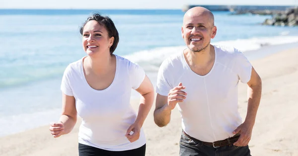 Uśmiechnięta Dojrzała Aktywna Para Białych Koszulkach Jogging Razem Dobrą Pogodę — Zdjęcie stockowe