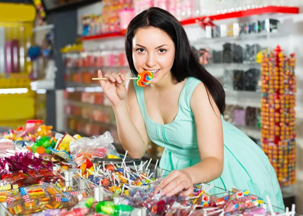 性感的女人在商店里摆出一副满意的姿势 莉莉站在柜台后面放着糖果 — 图库照片